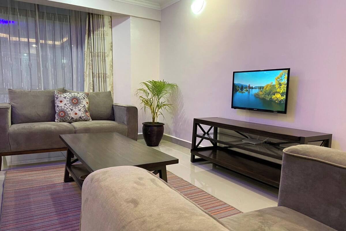 Una sala de estar moderna con un sofá, una mesa de centro, un televisor y una planta en maceta.