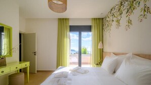 A hotel room with a bed, a desk, a mirror, and a view of the outdoors.
