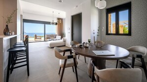 Ein moderner Essbereich mit einem runden Tisch, mehreren Stühlen und Blick auf das Meer durch große Fenster.
