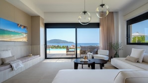 Ein modernes Wohnzimmer mit großem Fenster, einer Couch, einem Couchtisch und einem Strandbild.