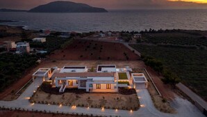 Eine moderne Villa mit Innenhof, umgeben von angelegten Gärten und Blick auf das Meer.