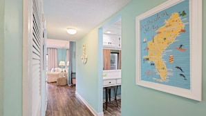 A hallway with a framed map of Southeastern States, a white desk, and a wooden floor. - Surfside Hideaway (Hilton Head Island)