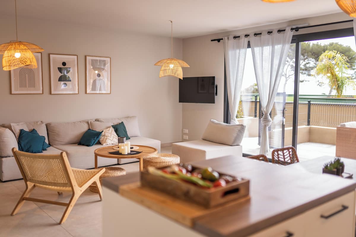 Uma sala de estar moderna com sofá, poltronas, mesa de centro e televisão na parede.