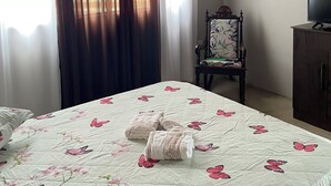 Une chambre à coucher avec un lit, une chaise, un téléviseur et des rideaux.