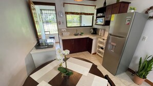 A compact kitchen with a dining table, a refrigerator, and a microwave. - Manuel Antonio a 100 Metros del mar (Quepos)