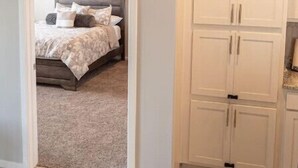 Um quarto com uma cama, um guarda-roupa branco e um quadro na parede.