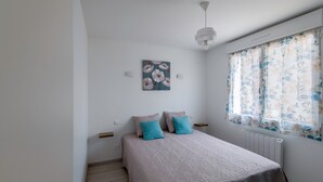 A bedroom with a bed, a wall-mounted painting, a window with curtains, and a ceiling light. - Logis de la Perruche - Maison avec terrasses (Montreuil-Bellay)