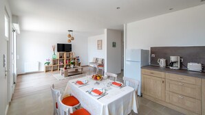A modern kitchen with a dining area, wooden cabinets, and a built-in oven. - Logis de la Perruche - Maison avec terrasses (Montreuil-Bellay)