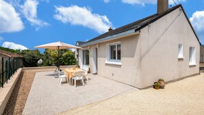 A house with a patio, a table with chairs, and a large umbrella. - Logis de la Perruche - Maison avec terrasses (Montreuil-Bellay)