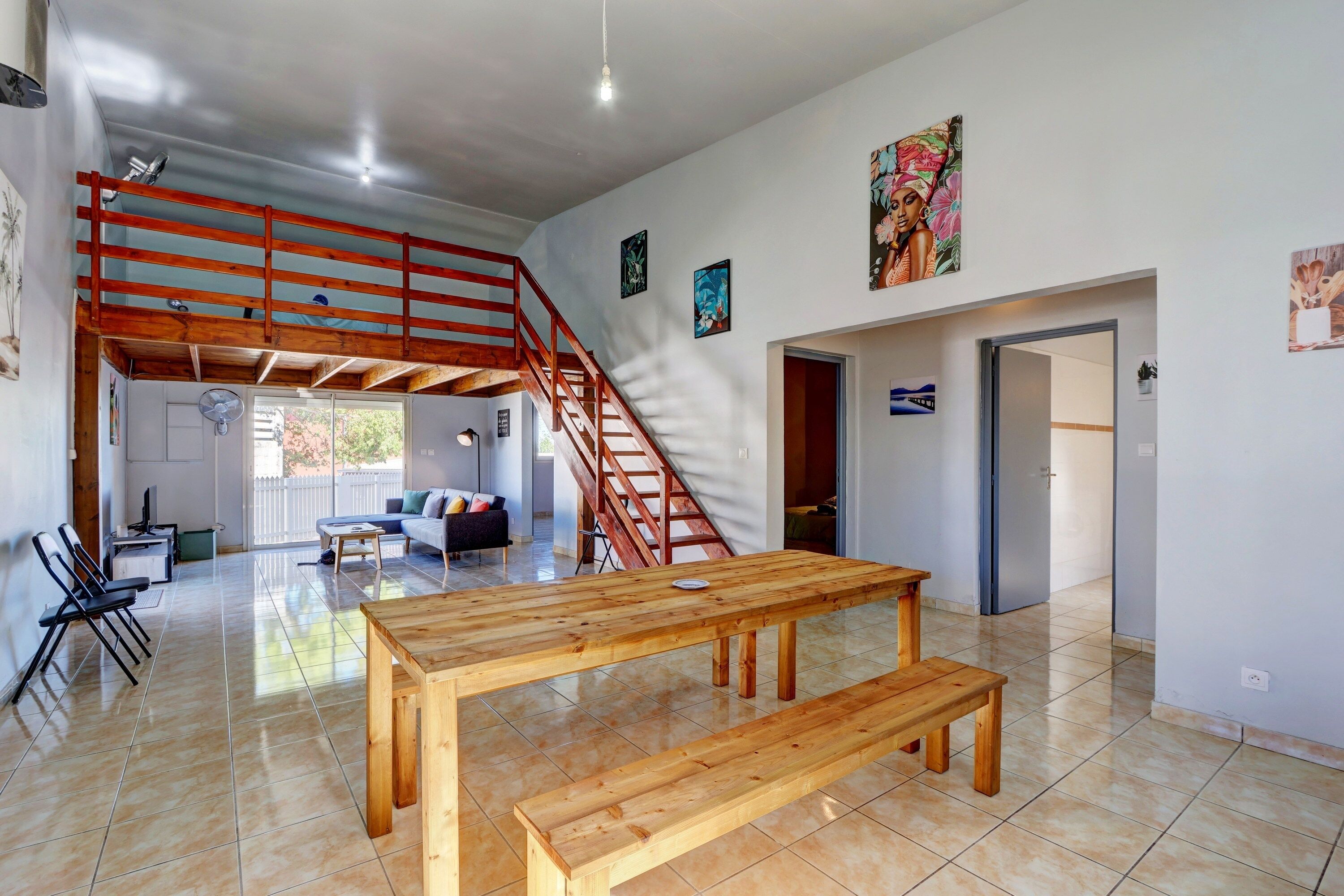 Un vaste espace de vie comprenant un banc en bois, un escalier et une table à manger.