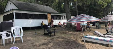 A beachside cabin with outdoor seating and umbrellas.