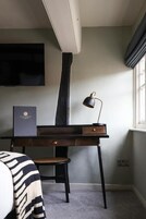 A room with a desk, chair, and a television mounted on the wall.