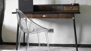 Una habitación moderna con un escritorio, una silla transparente, una lámpara y un espejo grande.