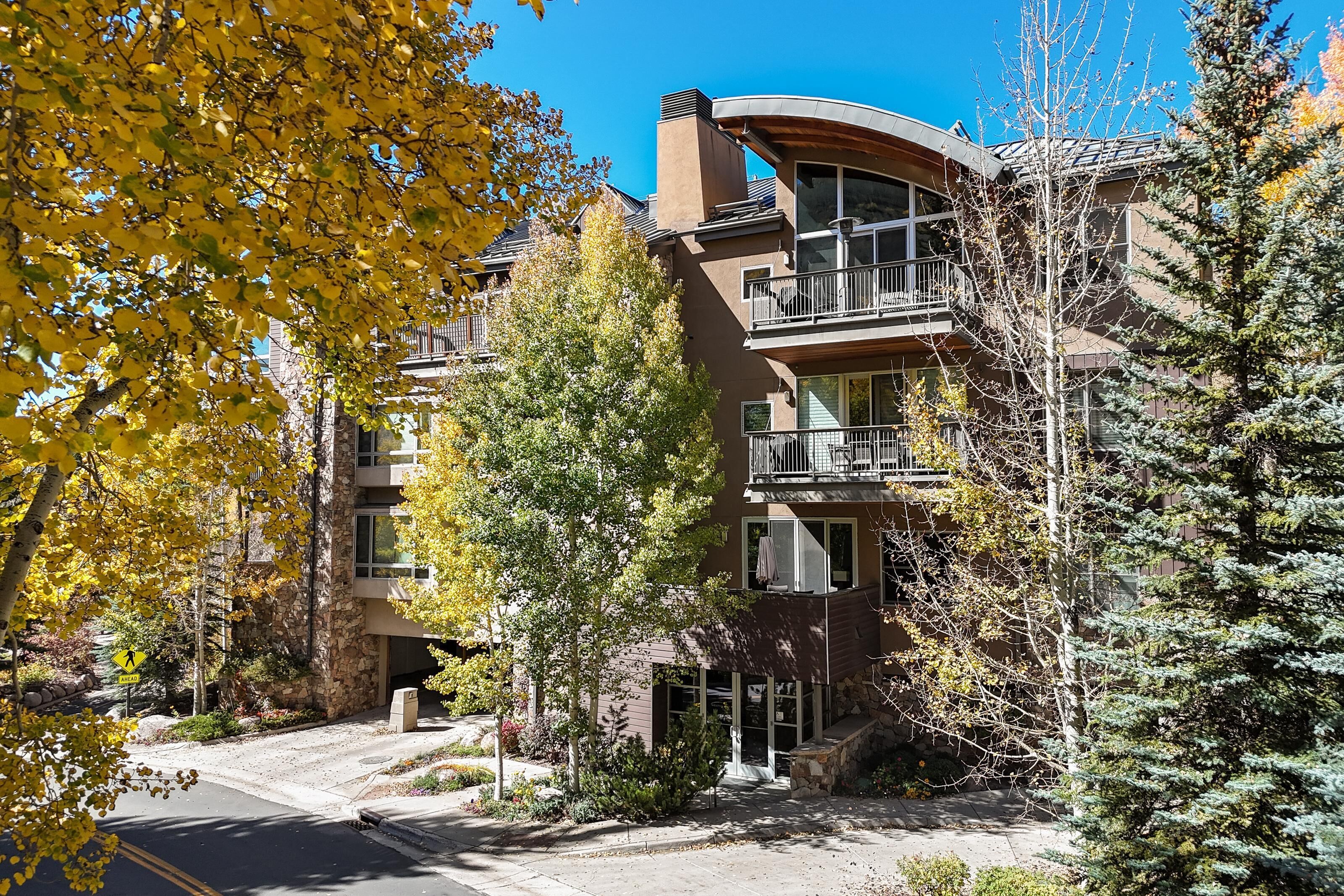 Un immeuble à plusieurs étages doté de balcons, d’une façade en pierre et d’un panneau indiquant un passage piéton.