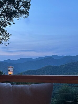 A view from a balcony overlooking a mountain range with a candle in a glass holder. - Appalachian Rainforest Oasis- breathtaking views surrounded by National Forest   (Barnardsville)