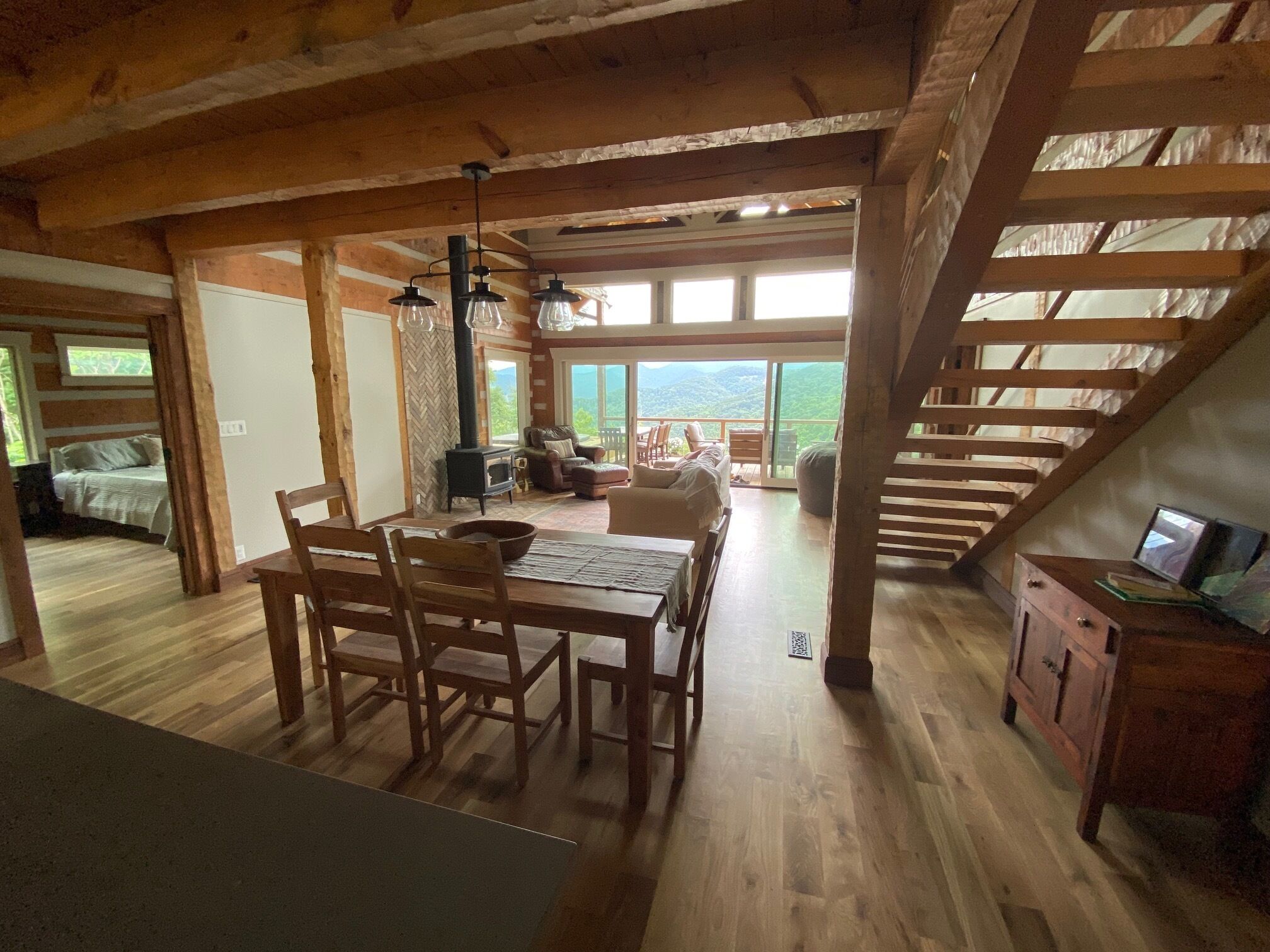 Un loft spacieux doté d’un coin repas en bois, d’un coin salon confortable avec une cheminée et d’une grande fenêtre offrant une vue sur l’extérieur.