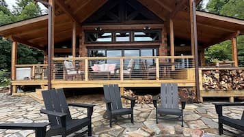 A wooden lodge with a stone patio, outdoor seating, and a fire pit.