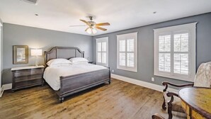 A bedroom with a bed, nightstand, lamp, and a ceiling fan.