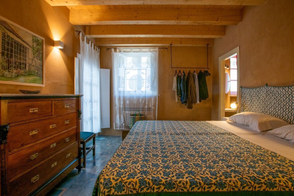 Une chambre à coucher avec un grand lit, une commode en bois et un tableau accroché au mur.