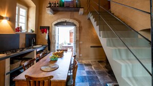 A spacious kitchen with a long wooden table, a built-in stove, and a staircase leading to an upper level. - House with direct sea access in Sampieri with 3 bedrooms (Sampieri)