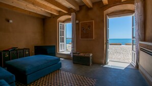 A bedroom with a wooden ceiling, a blue bed, a view of the beach through an open door, and a patterned rug. - House with direct sea access in Sampieri with 3 bedrooms (Sampieri)