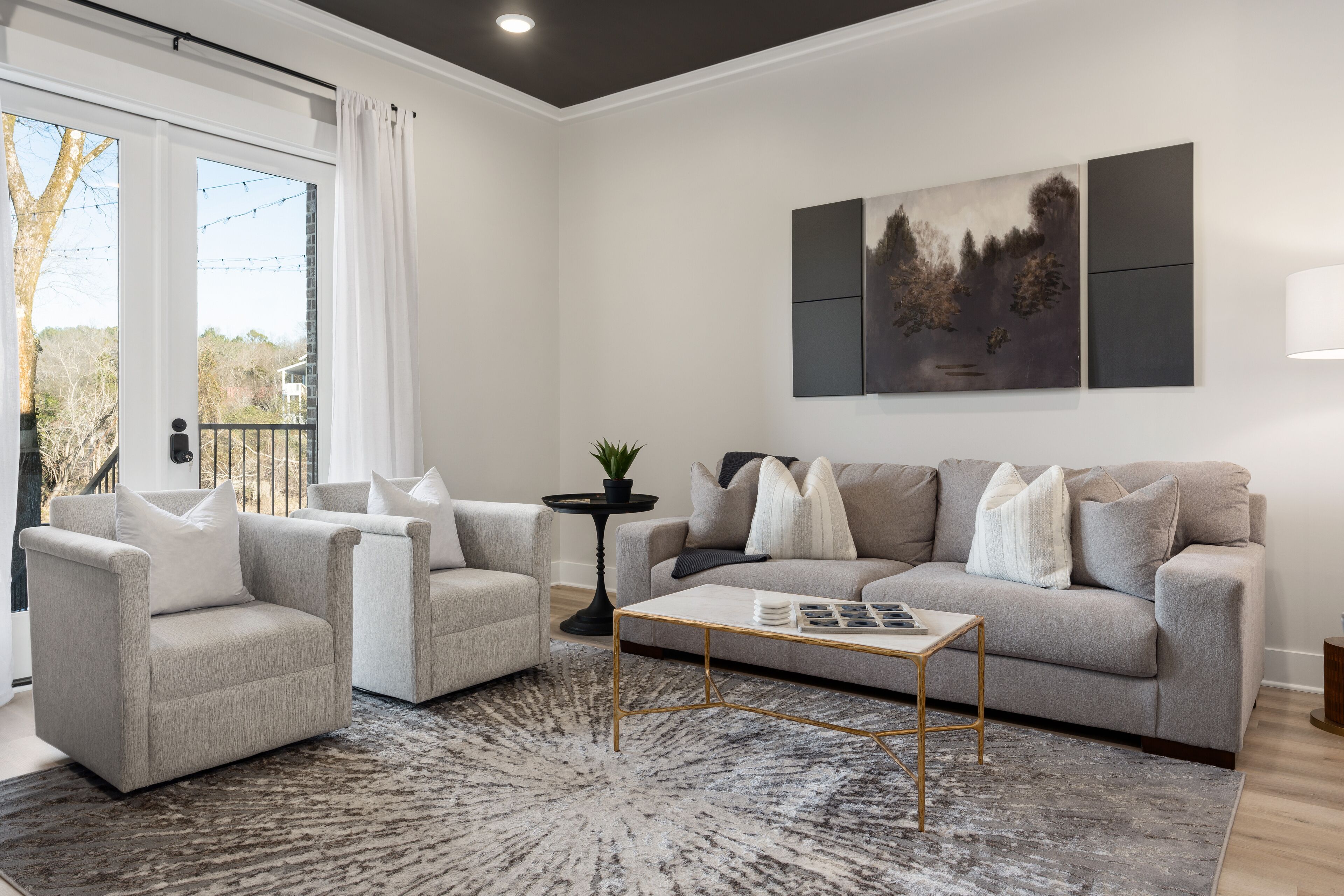 A living room with a grey sofa, two armchairs, a coffee table, and a rug.