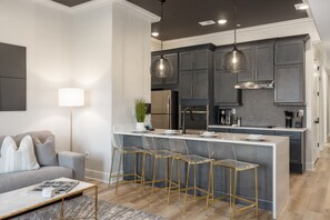 Una cocina moderna con una isla central, taburetes de bar e iluminación colgante.