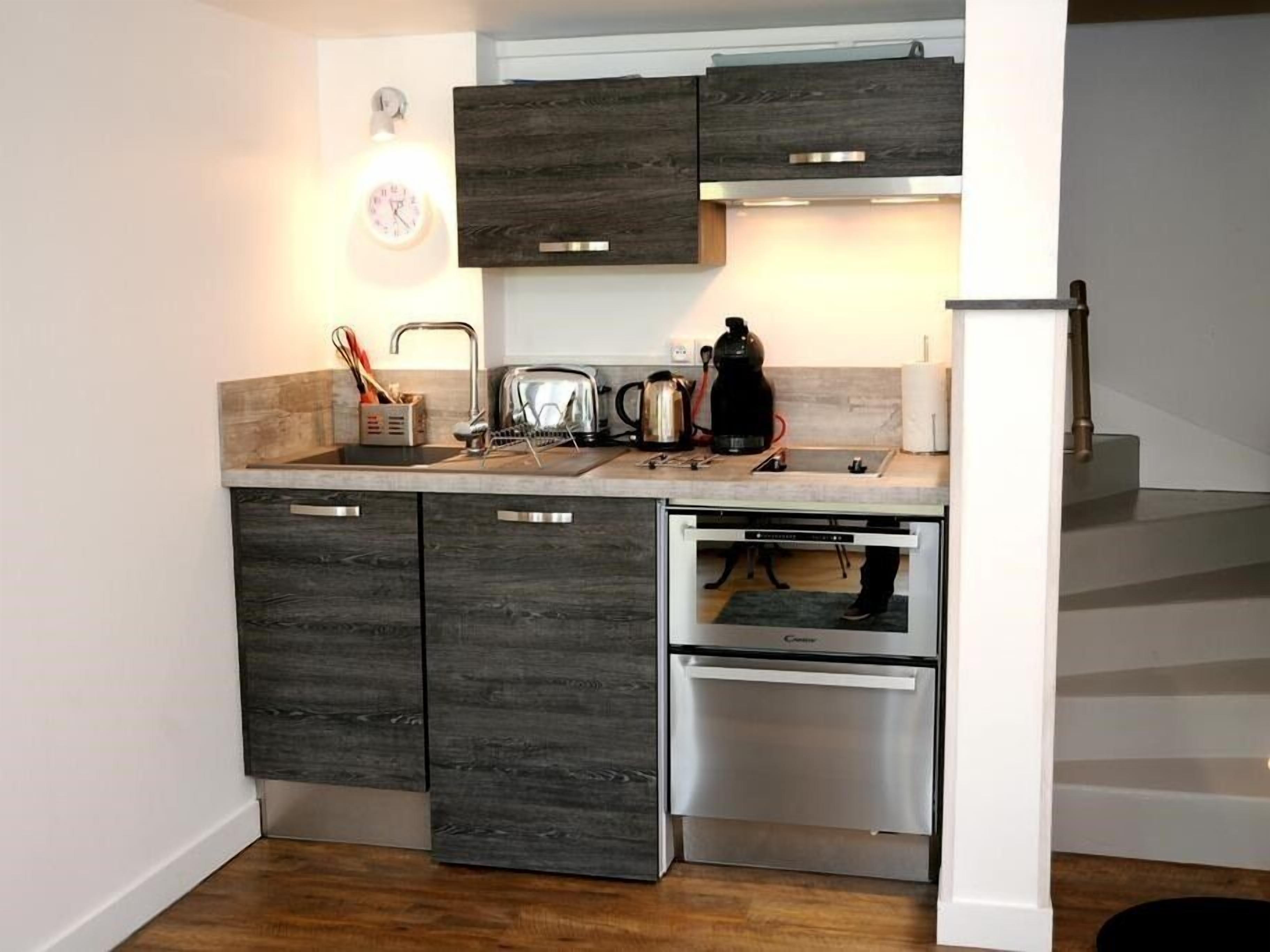 A compact kitchen with dark wood cabinets, a built-in oven, and a toaster.