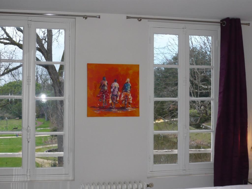 A room with two windows, a radiator, and a painting on the wall.