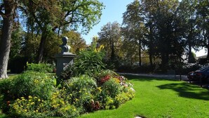 Une statue dans un parc, entourée d’une végétation luxuriante et d’arbres.