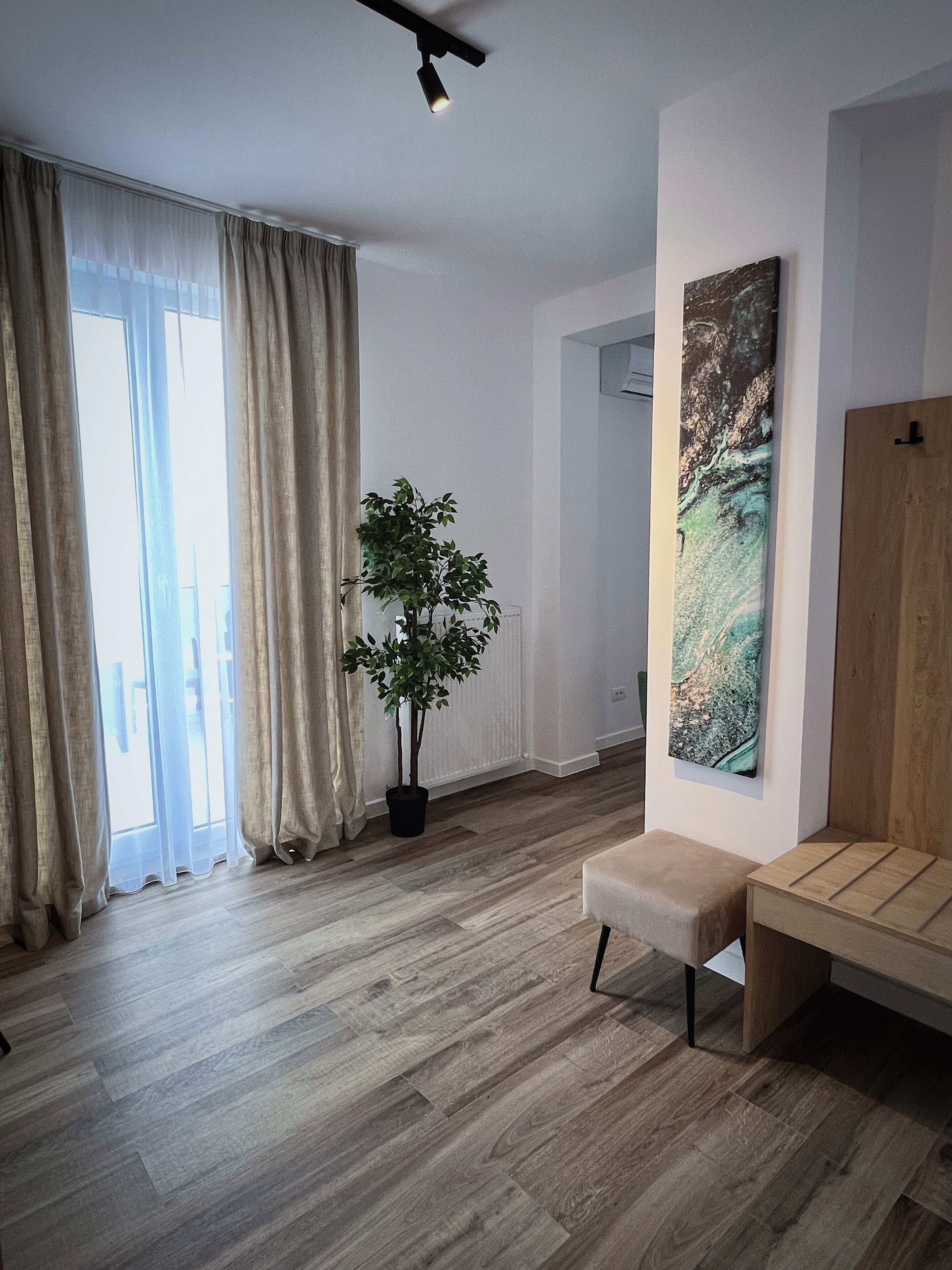 A modern living room with a wooden bench, a potted plant, and a large abstract painting on the wall.