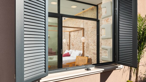 Une chambre moderne avec une grande fenêtre, un lit, une table de chevet et une chaise.