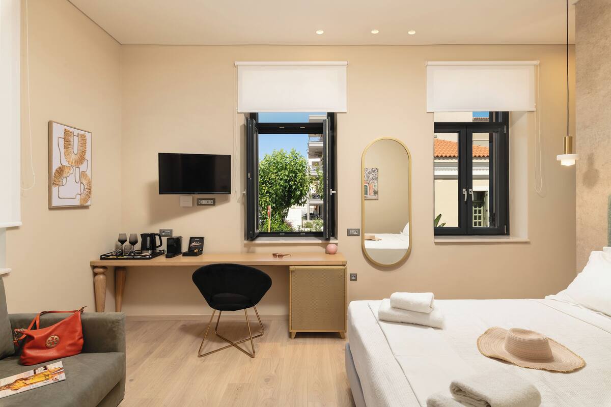 Een moderne hotelkamer met een bed, een bureau, een televisie en een raam met uitzicht op de stad.
