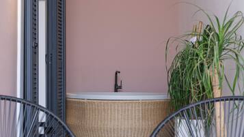 Een moderne badkamer met een bad, een potplant en twee rieten stoelen.