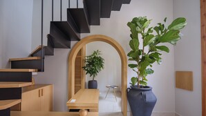 Un intérieur moderne avec un escalier en bois, une grande plante en pot, une table en bois et une petite table ronde surmontée d’un globe terrestre.