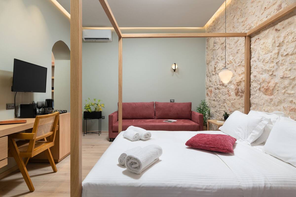 Een moderne hotelkamer met een bed, een bureau, een televisie en een rode bank.