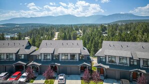 A row of modern, two-story houses with a view of mountains and forest in the background. - The Bauhaus | Private Hot Tub | Walk to Lake | MCM (Invermere)