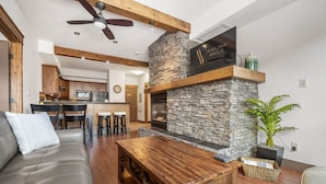 Una sala de estar moderna con chimenea de piedra, una mesa de centro de madera y un sofá gris.