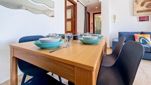 A dining area with a wooden table set for four, blue chairs, and a modern ceiling design.