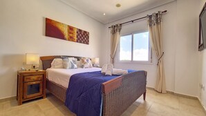 A bedroom with a bed, nightstand, lamp, and a painting on the wall.
