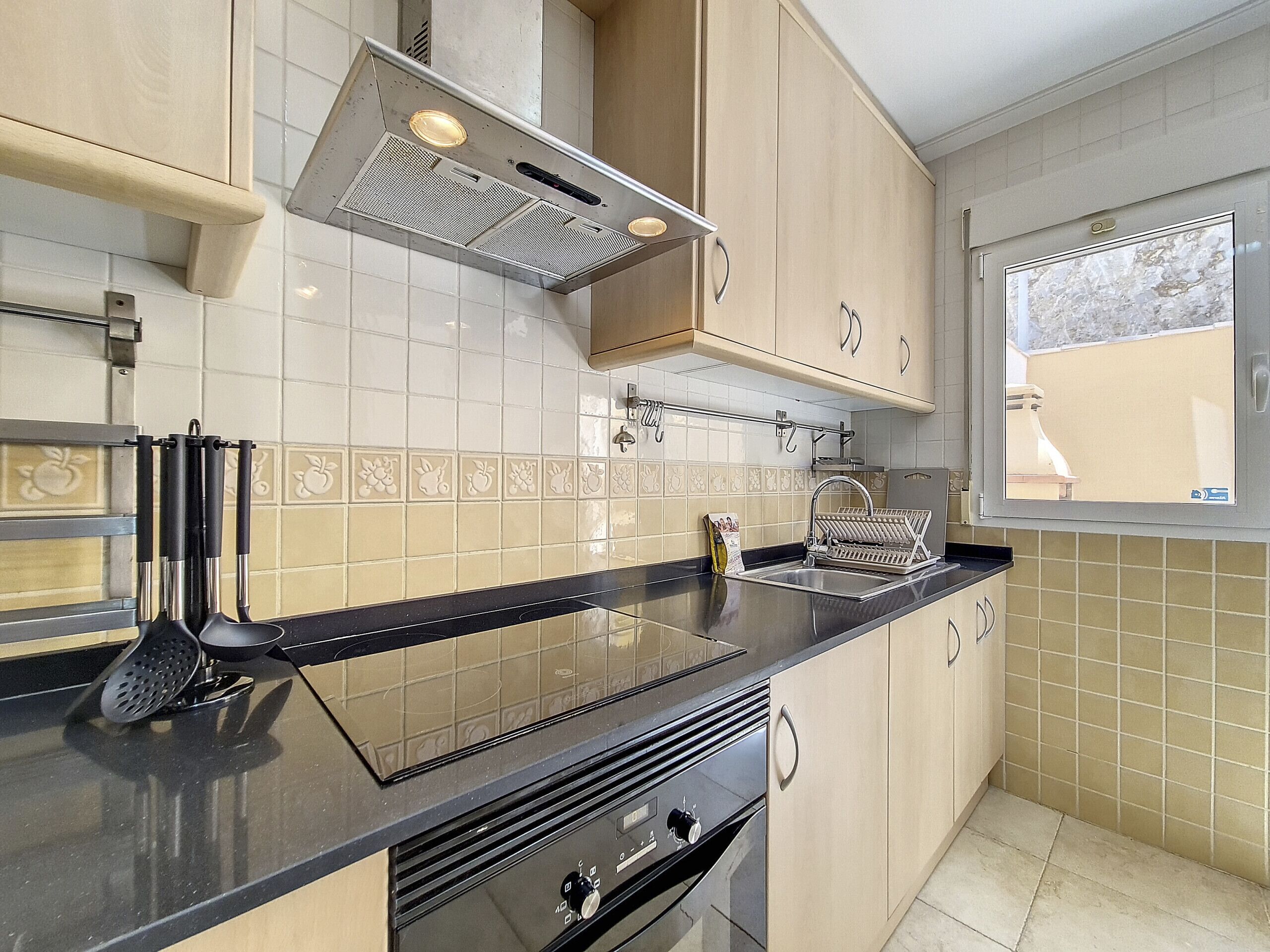 A modern kitchen with a black countertop, stainless steel appliances, and beige cabinetry.