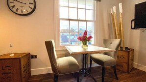 A dining area with a table, two chairs, a clock, a window, and a vase with flowers. - Stunning Little House on Poole Quay -Free Parking (Poole)