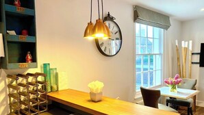 A modern kitchen with a wooden island, pendant lights, a clock, and a view of the city through a large window. - Stunning Little House on Poole Quay -Free Parking (Poole)