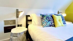 A hotel room with a bed, bedside lamps, a nightstand, and a wooden stool. - Stunning Little House on Poole Quay -Free Parking (Poole)