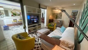 A modern living room with a sofa, yellow armchair, and a TV. - Ocean Front Copacabana - 1 min from the beach (Rio de Janeiro)