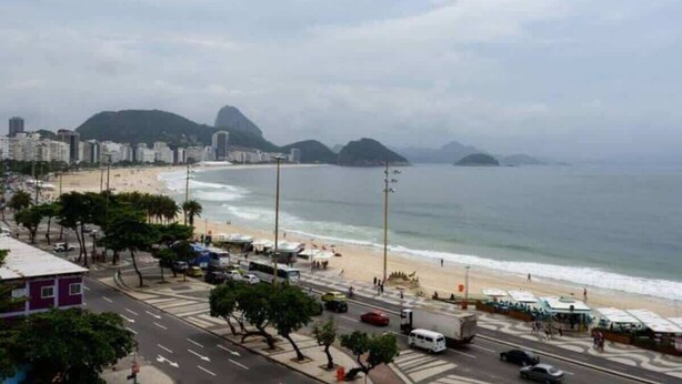 A coastal cityscape with a beach, urban buildings, and a prominent mountain in the background. - Ocean Front Copacabana - 1 min from the beach (Rio de Janeiro)