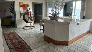 A modern kitchen with a central island, a hanging chair, and a view of the ocean. - Ocean Front Copacabana - 1 min from the beach (Rio de Janeiro)