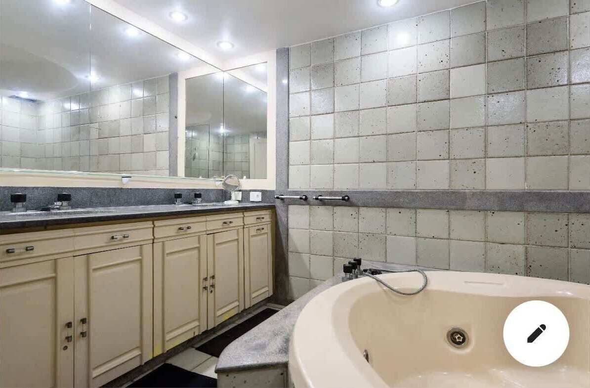 Une salle de bain dotée d’une grande baignoire, d’un meuble-lavabo à deux vasques et d’un miroir au-dessus du lavabo.