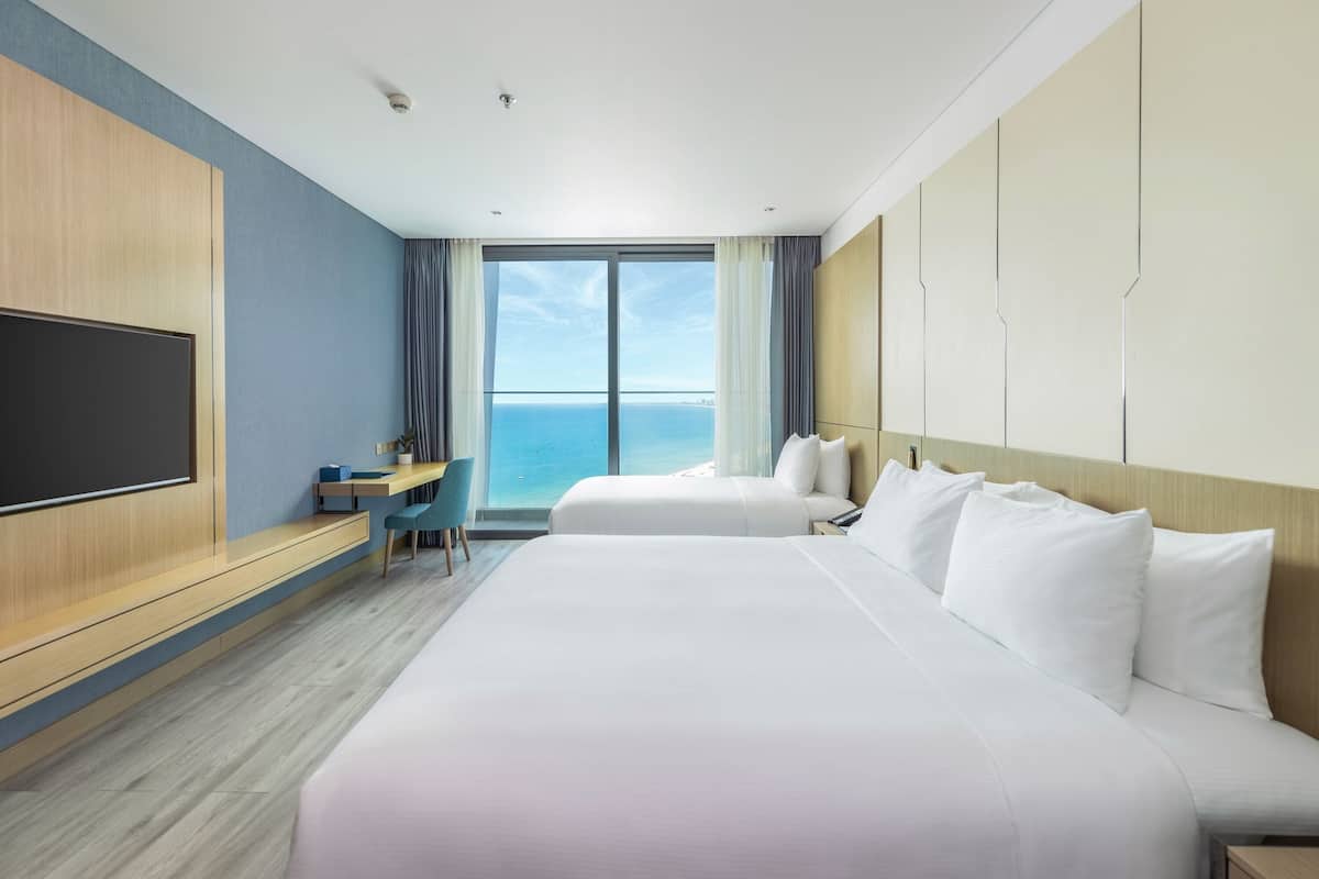 A modern hotel room with a large bed, a desk, and a TV.