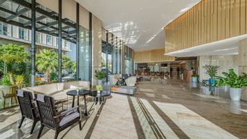 A spacious lobby with a high ceiling, large windows, and a seating area with modern furniture.